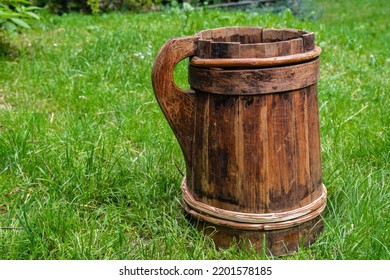 Old And Cracked Wooden Buckets Traditional Water Container .wooden Bucket Old And Weathered With A Handle Stands On The Grass Close-up