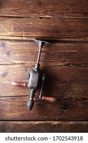 Old Crank Drill Hanging On A Rustic Wooden Wall