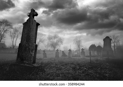 Old creepy graveyard on stormy winter day in black and white.
