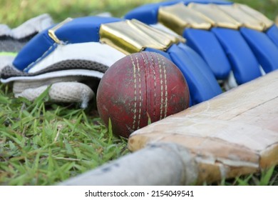 Old Cricket Sport Training Equipments On Grass Floor, Leather Ball, Wickets, Gloves And Wooden Bat, Soft And Selective Focus, Traditional Cricket Sport Lovers Around The World Concept.