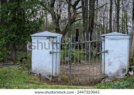 old crooked cemetery gate with white columns. Jačūnu kapi, Latvia, Zemgale