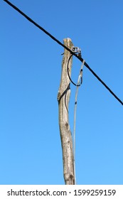Old Crooked Wooden Electrical Utility Pole Connected With Thick Electrical Wires On Clear Blue Sky Background