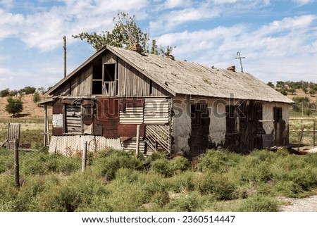 Old crumbling house with boarded up windows in rural area in Kazakhstan
