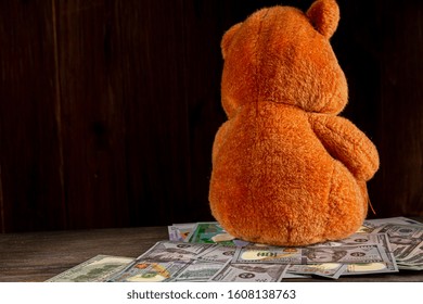 An Old, Crumpled Dollar And A Small Children's Toy. Alimony, Children's Pocket Money. The Background Is Blurred. A Toy Of Mass Production