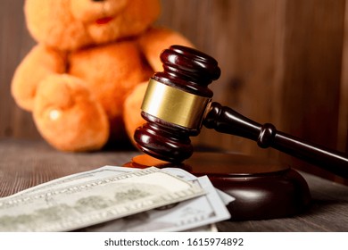 An Old, Crumpled Dollar And A Small Children's Toy. Alimony, Children's Pocket Money. The Background Is Blurred. A Toy Of Mass Production