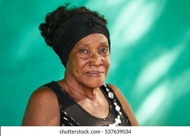 Old Cuban people and emotions, portrait of happy senior african american lady looking at camera. Copy space on green wall in background.