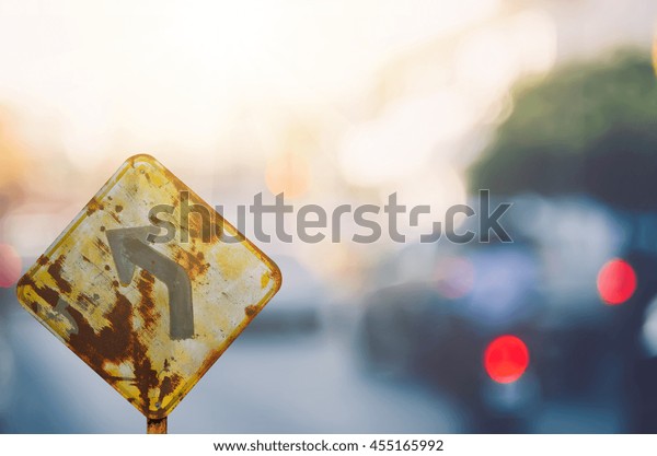 Old curve road\
warning sign on blur traffic road with colorful bokeh light\
abstract background. Copy space of transportation and travel\
concept. Retro tone filter color\
style.