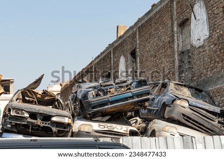 Old damaged cars on the junkyard waiting for recycling in city.