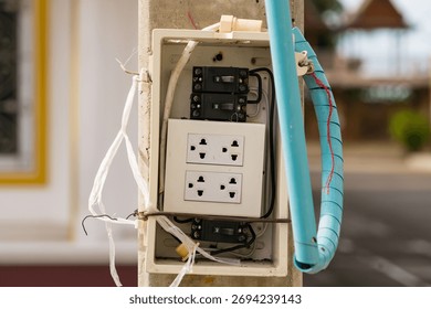 Old damaged electrical switchboard mounted on wall with exposed wiring and multiple power sockets in unsafe condition