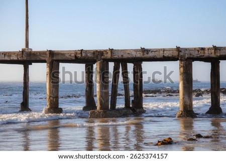 Old damaged jetty going into the ocean with clear blue sky background