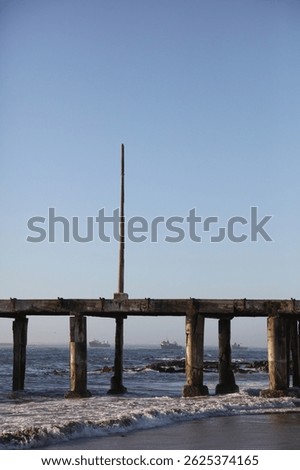 Old damaged jetty going into the ocean with clear blue sky background