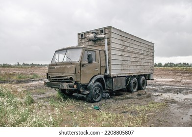 Old damaged Soviet refrigerator truck in field. Abandoned car under rain, cargo truck