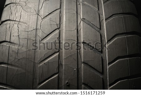 Old damaged, worn black tire tread, large cracks in the car wheel, tire black color for background. Macro removed from the old thread.