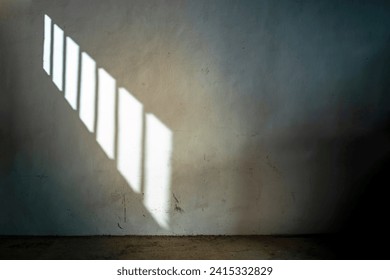 OLD DARK CELL IN JAIL OR PRISON WITH SUNLIGHT COMING THROUGH THE BARRED WINDOW. PRISONER SERVING SENTENCE.