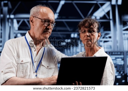 Old data storage company executives doing diagnostic assessments on high tech workspace servers. Engineers during yearly maintenance looking for potential system shortcomings