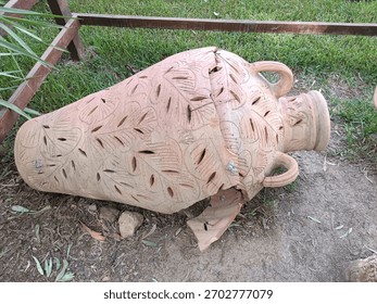 An old, decorated, broken pot lying on the ground