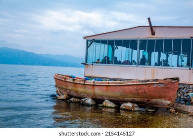 An old decrepit rowboat is stranded on the edge of the lake restaurant. Lake view restaurant. Rotten boat.