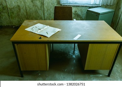 Old Desk In Abandoned Office With Sheet Of Paper On It