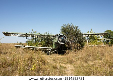 Old devastated biplane with a single motor and no blades as a sign of old machinery that is already obsolete and standing on plane cemetery