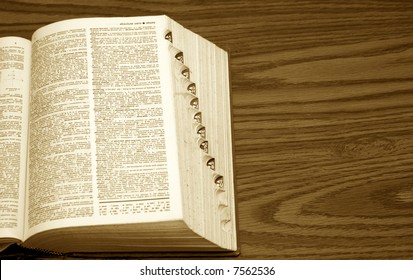 Old Dictionary With Page Open, Showing Side Tabs On Desk In Sepia