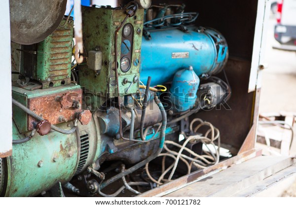 Old diesel generator with oil stains. Vintage\
engine. Trailer with the old diesel compressor. Mobile compressor\
parked at building site.\
Diesel.