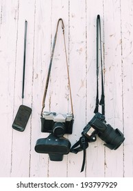 Old And Digital Photo Cameras Are Hanging On The Wooden Wall