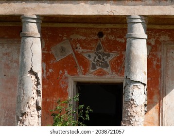 Old dilapidated building with columns and a hammer and sickle symbol over the door,