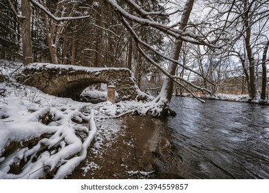 An old, dilapidated stone bridge over the river Divoká Orlice on the Czech-Polish border in the Orlické Mountains. The first snow.