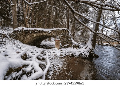 An old, dilapidated stone bridge over the river Divoká Orlice on the Czech-Polish border in the Orlické Mountains. The first snow.