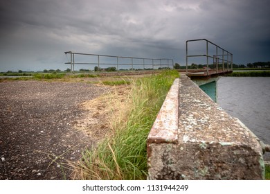 Old and dilapidated vintage rampart along the waterfront in a river landaschap of the Netherlands. Concrete mooring jetty in abandoned state. - Powered by Shutterstock