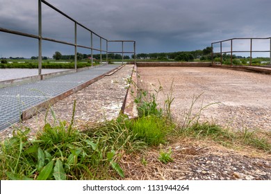 Old and dilapidated vintage rampart along the waterfront in a river landaschap of the Netherlands. Concrete mooring jetty in abandoned state. - Powered by Shutterstock