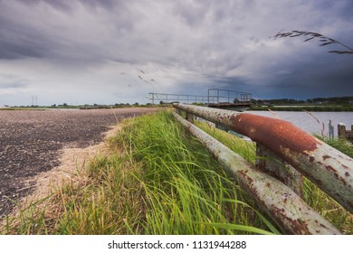 Old and dilapidated vintage rampart along the waterfront in a river landaschap of the Netherlands. Concrete mooring jetty in abandoned state. - Powered by Shutterstock