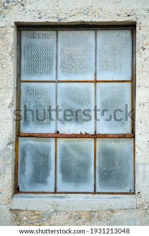 An old dingy window with rust and concrete.