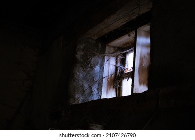 An Old Dirty, Creepy, Cobweb-strewn Window In A Dark Cellar