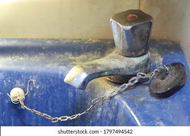 Old and dirty faucet and dark blue ceramic washbasin sink,with limescale and become rutted.concept of cleaning, replacing a bathroom, toilet.
