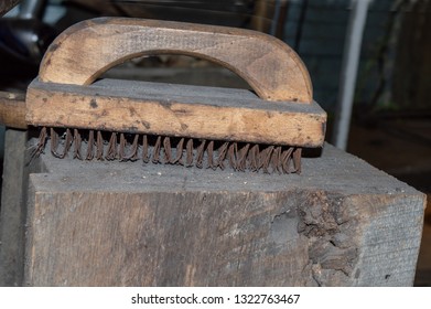 An old dirty and grungy wire brush on a block of wood inside the blacksmith shop in Missouri. Bokeh effect. - Powered by Shutterstock