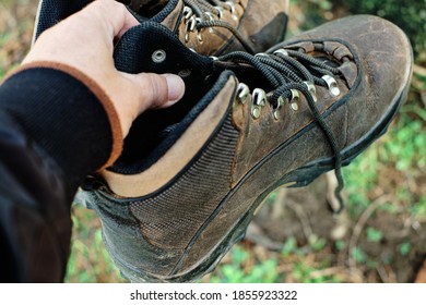 Old Dirty Hiking Boots Holding One Hand