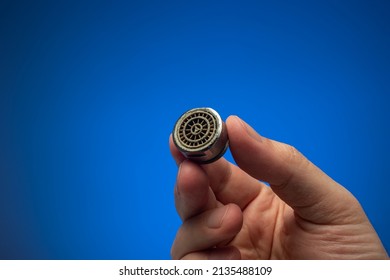 Old Dirty Limescale Covered Clogged Up Tap Water Faucet Strainer Or Aerator Held In Hand By Caucasian Male. Close Up Studio Shot, Isolated On Blue Background.