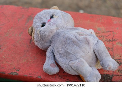 Old Dirty Toy Plush Cat Lies On A Bench.