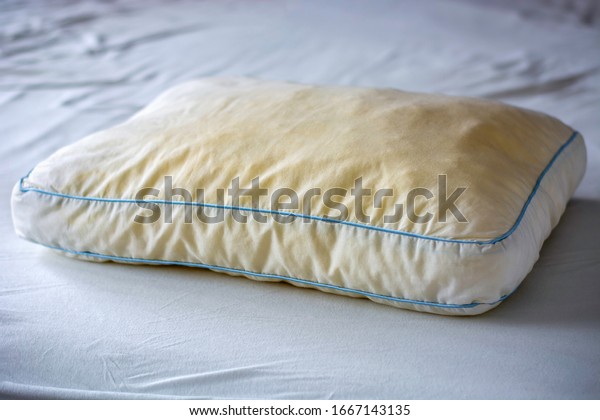 Old dirty\
used yellow sweat stained sleep pillow on a mattress. Condition of\
the pillow used for a long time.\
