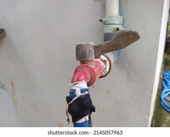 Old And Dirty Water Faucet Connected To The Blue Water Hose