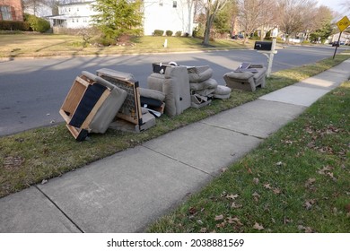 Old disassembled chairs and cushions lined up by the curb waiting to be disposed of by the garbage men on trash day