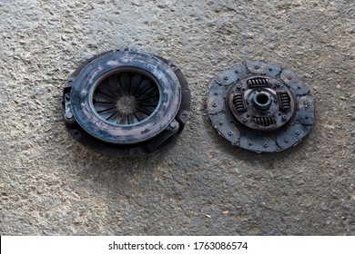 Old Disc Clutch And Cover On Floor. Old Rusty Clutch And The Disc Lies In The Garage. Car Rusty Clutch Pressure Plate Assembly  With Clutch Disc Plate And Fly Wheel