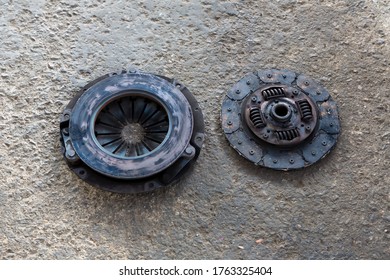 Old Disc Clutch And Cover On Floor. Old Rusty Clutch And The Disc Lies In The Garage. Car Rusty Clutch Pressure Plate Assembly  With Clutch Disc Plate And Fly Wheel