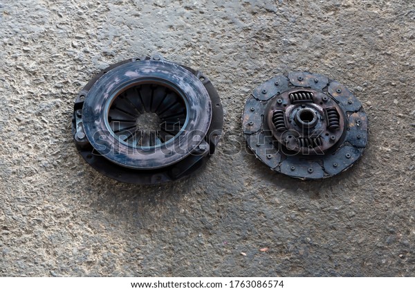 Old Disc Clutch and cover\
on floor. Old rusty clutch and the disc lies in the garage. Car\
rusty clutch pressure plate assembly  with clutch disc plate and\
fly wheel