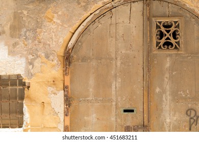 Old distressed yellow wooden double-door, in Maltese Limestone wall, shot straight-on in Valletta, Malta, Europe. Used in the 2015 filming of the Assassin's Creed movie.