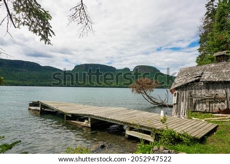 Old dock and rundown shed with hills, lake and forest in background