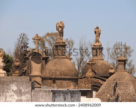 Old Domes of cemetery mausoleums made of stone decorated with statues of angels and crosses with blue sky background