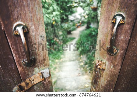 Old door handles on the opened door and see through the blurred walkway background.