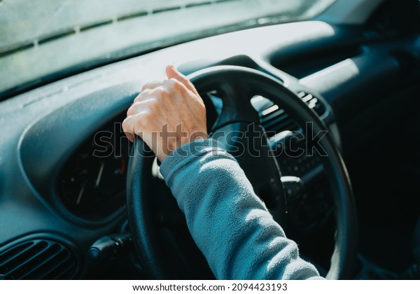 Old driver hands holding steering wheel driving\
a car. Learning to drive a car. Safety drive. Learning new hobby,\
habit and skill for this new year. Elderly person approving the\
driving license.